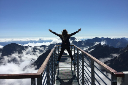 An illustrative photo of a person standing on a viewing platform with mountains visible