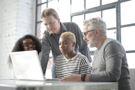 An illustrative photo of four people looking in the laptop