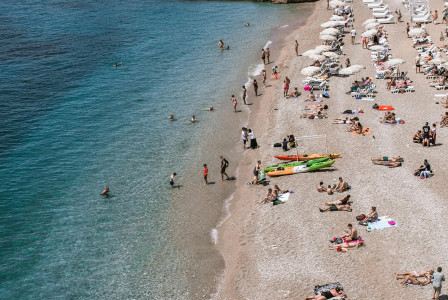 An illustrative photo of a beach scene with people sunbathing and swimming