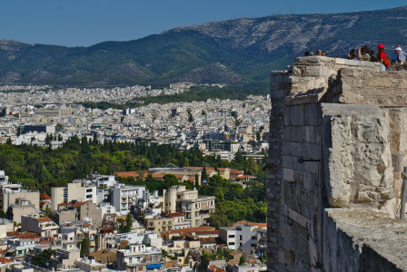 An illustrative photo of a group of people standing on top of a tall building with a cityscape in the background