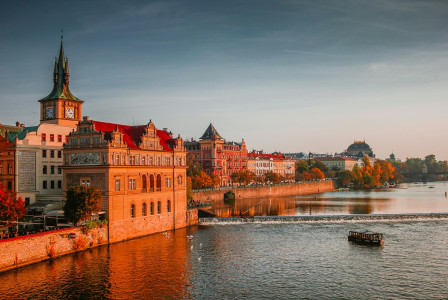 An illustrative photo of a boat in the river near high rise buildings in Prague