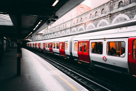 An illustrative photo of a white and red train is captured beside a building during daytime
