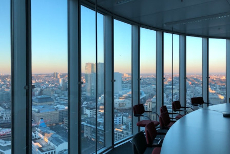 An illustrative photo of people sitting on chairs near a large glass window during the daytime