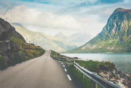 An illustrative photo of a two-lane road winding around a lake.