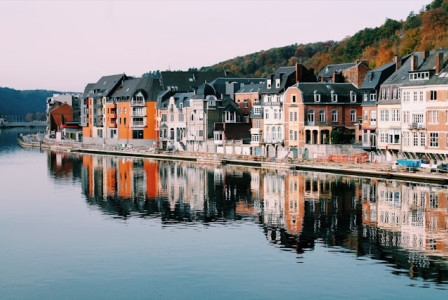 An illustrative photo of assorted colorful houses line the shore of a serene lake.
