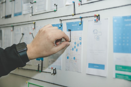 An illustrative photo of a person working on a blue and white paper on a board