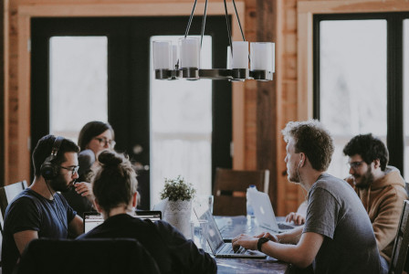 An illustrative photo of people sitting beside a table inside a room