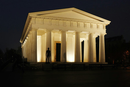 Photo by Unsplash An illustrative photo of a neoclassical building illuminated at night with a silhouette of a person standing in the entrance
