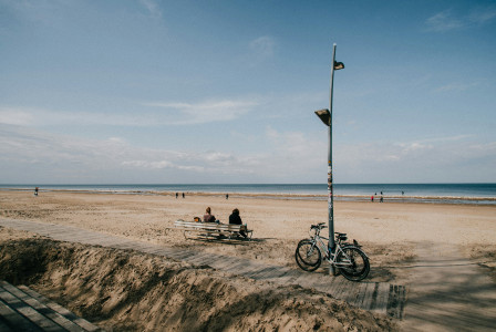 An illustrative photo of a man and woman sitting on beach during daytime.