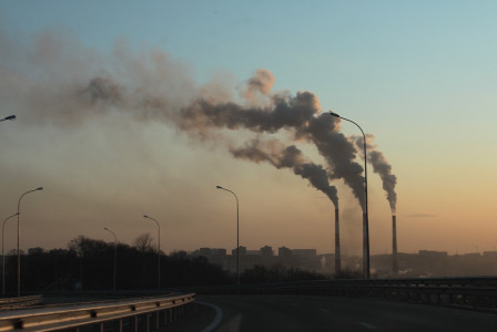 An illustrative photo of a factory emitting smoke against a dusky sky
