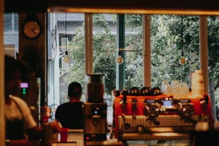 Photo by Unsplash An illustrative photo of a man sitting at a table in front of a window.