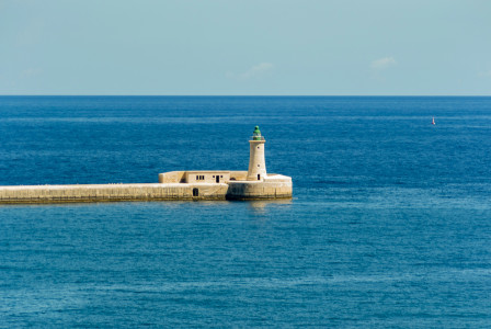 An illustrative photo of a lighthouse on a dock in the middle of the ocean.
