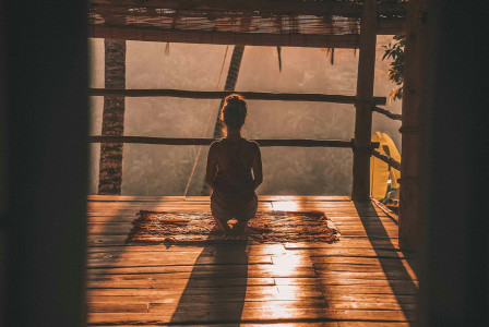 An illustrative photo of a woman meditating on floor.