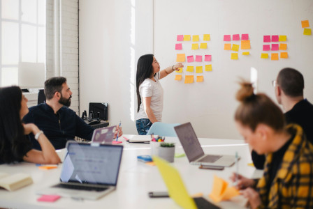 An illustrative photo of a group of people in a bright room, engaged in a collaborative work session.