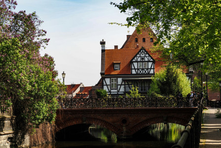 An illustrative photo of a bridge over a river with a house in the background.