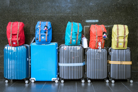 An illustrative photo of a row of colorful luggage with backpacks on top