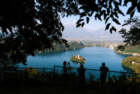 An illustrative photo of a group of people standing on top of a hill next to a lake.