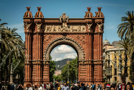 An illustrative photo of people standing near brown arched gate.