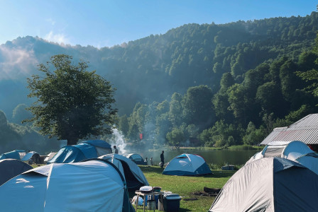 An illustrative photo of tents in a camp by a lake.
