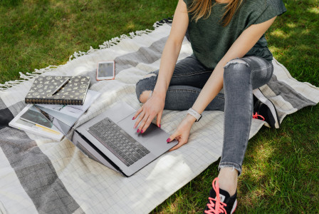 An illustrative photo of a female working on laptop while studying in park