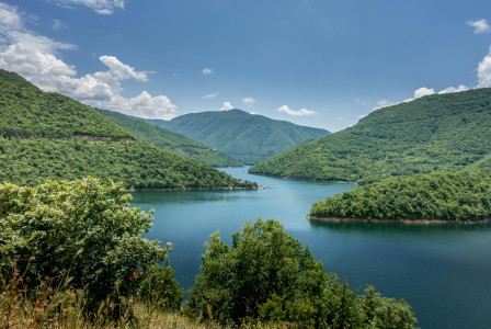 Photo by Pexels An illustrative photo of a lake nestled within a valley, surrounded by lush green hills under a partly cloudy sky
