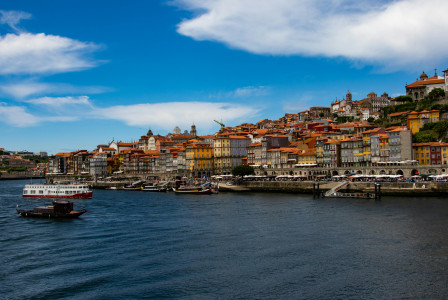 An illustrative photo of  a panoramic view of a colorful riverside cityscape with traditional buildings and boats on the water