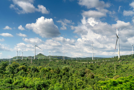 An illustrative photo of white wind turbines under a cloudy sky
