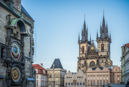 An illustrative photo of a building with clock and with church in the backround
