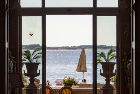 An illustrative photo of a view through an open doorway leading to a waterfront scene..
