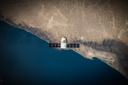 An illustrative photo of a pace satellite hovers above a coastline.