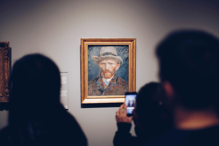 An illustrative photo of a person taking picture of a painting.