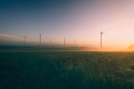 An illustrative photo of windmills standing against a stunning sunrise