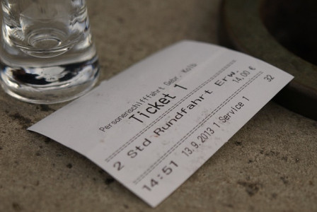 An illustrative photo of a ticket, glass, and paper receipt on a surface