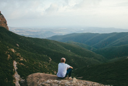 An illustrative photo of a person sitting on the edge of a cliff