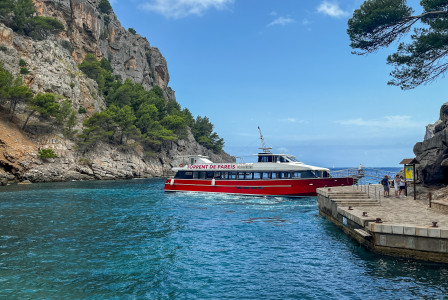 An illustrative photo of a red and white boat in a body of water near rocky mountain