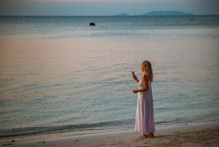 An illustrative photo of an individual standing on a beach at sunset.