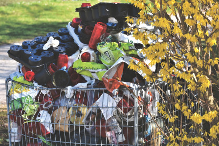 An illustrative photo of a shopping cart filled with various discarded items and recyclables