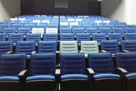 An illustrative photo of rows of blue and white chairs in a big room