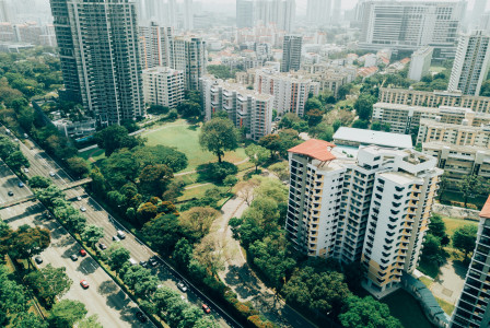 An illustrative photo of a city with skyscrapers and a lot of green trees 