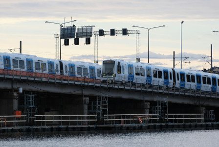 An illustrative photo of a blue and white train driving over a bridge