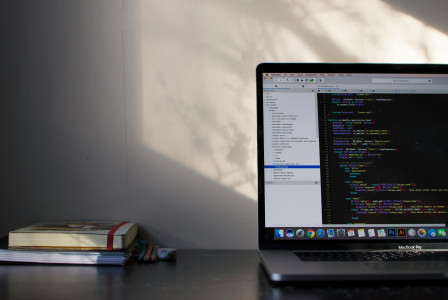 An illustrative photo of a laptop on a table with programming language on its screen