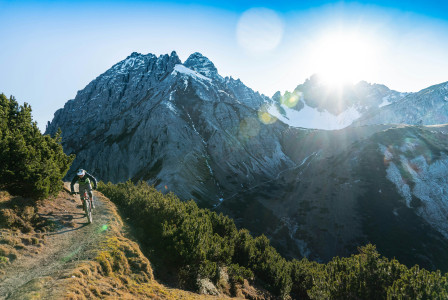 An illustrative photo of a person riding a bike on a trail in front of a mountain