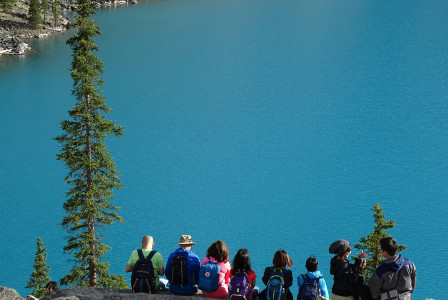 An illustrative photo of people sitting on rock edge facing body of water