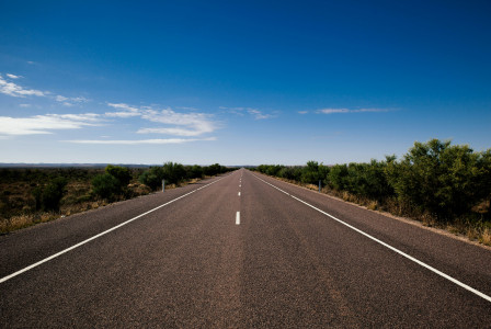 An illustrative photo of  a straight road leading towards a horizon
