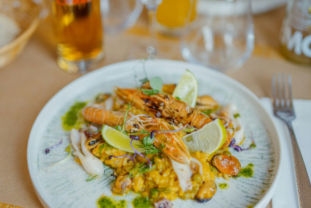 An illustrative photo of a plate of food on a table with wine glasses