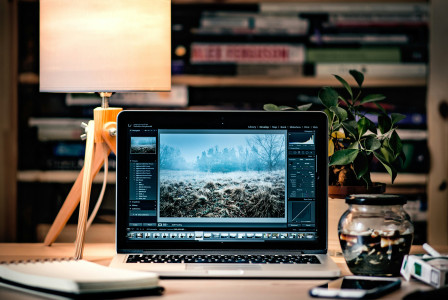 An illustrative photo of a laptop on a wooden table beside a lamp