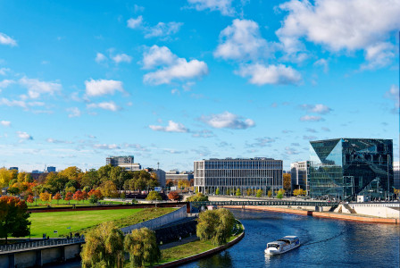 An illustrative photo of a river running through a city next to a tall building