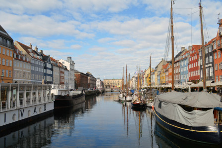 An illustrative photo of several boats docked in the water next to a row of buildings.
