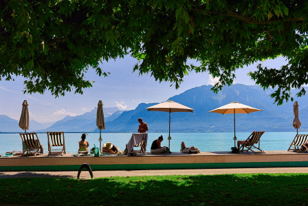 An illustrative photo of people sitting under umbrellas.