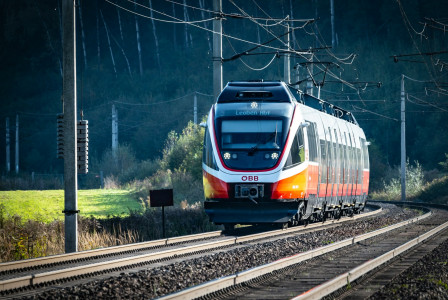 An illustrative photo of a train traveling down train tracks next to a forest